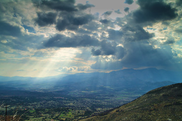 Sun rays through the clouds mountains and valley , in Arcadia Greece.