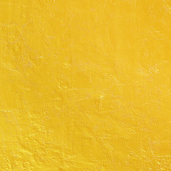 Gold paint on rough cement wall texture.