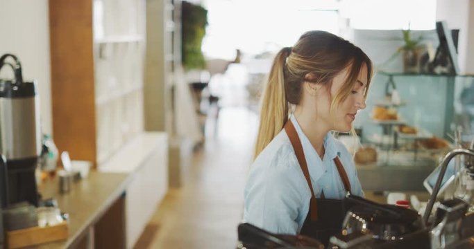 Young attractive female barista making coffee, barista preparing espresso in coffee shop, artisan coffee shop lifestyle