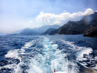 Fototapeta na wymiar Landscape with sea, mountains and wave from boat in a summer day