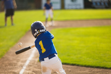 Youth baseball player hitting ball