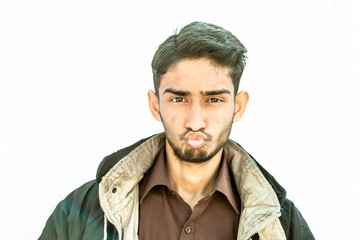 Portrait shot of young teenager beard wearing a maroon colored shirt and a black colored jacket expressing doubtfulness on his face isolated on white.