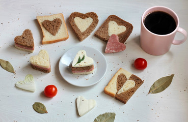 Delicious composition - sandwiches and bread in the form of hearts on the table