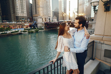 beautiful long-haired girl in summer dress with her handsome husband in white shirt and pants...