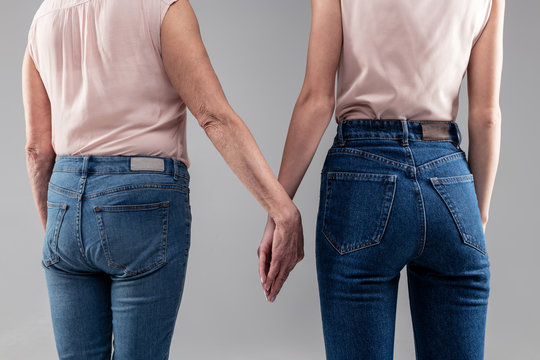 Young lady and her senior mother wearing blue jeans and nude tops