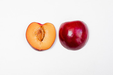 Sliced red blue plum isolated on white background one cut in two halves.