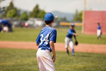 Youth shortstop throwing to first baseman