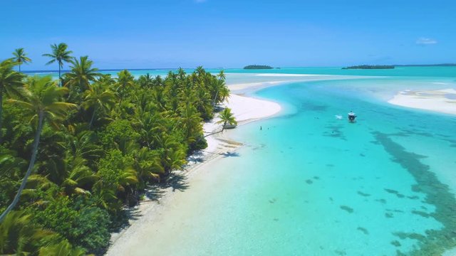 AERIAL: Flying along the idyllic white sand shore and tourists anchoring their boat and cooling off in the pristine turquoise ocean. Local people enjoying by One Foot Island in the peak of summertime.