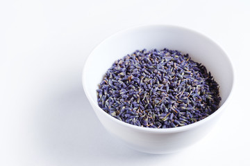 Dried lavender in a white porcelain bowl on a white background