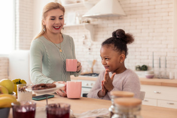 Cute daughter feeling excited getting cup of tea in the morning