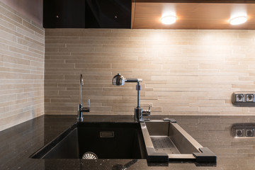 Black artifical stone countertop with black sink and two faucets