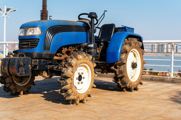 Blue tractor on the background of an empty field and a clear blue sky