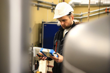 Engineer with measure tester on heat boiler