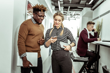 Active long-haired girl displaying her smartphone screen to interested guy