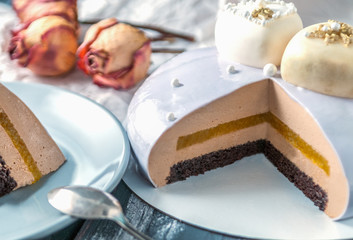 Split biscuit cake covered with mirror glaze. In the context of orange confiture, coffee and Bavarian mousse. 