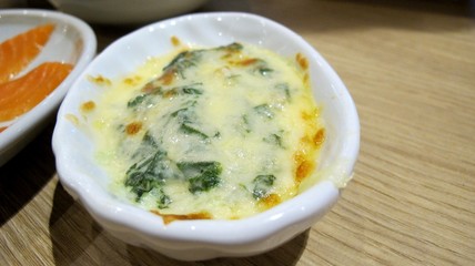 Closed up Baked spinach with cheese  in a white cup, delicious food