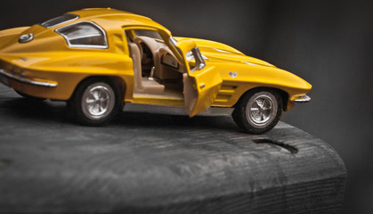 Naklejka premium Toy car model Corvette Sting Ray 1963 year. Yellow color. Side view. Opened door. Close-up. Macro. Isolated.
