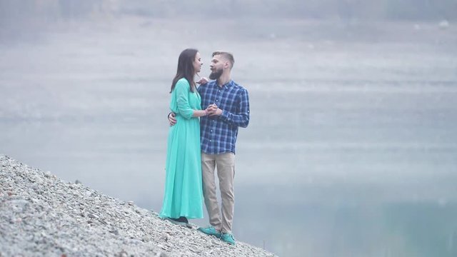 young fashionable family young man with a beard and a woman in a long dress during a photo session at the lake
