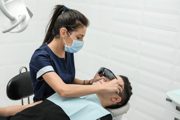 Patient on reception at the dentist. Woman's doctor sets up equipment before dental treatment.