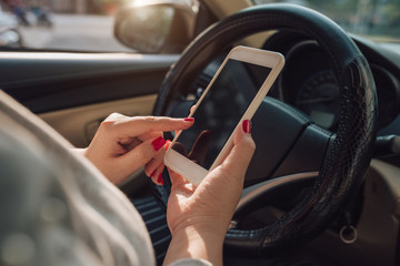 Mockup image of woman hand using mobile smartphone with blank screen while driving car and leaving...