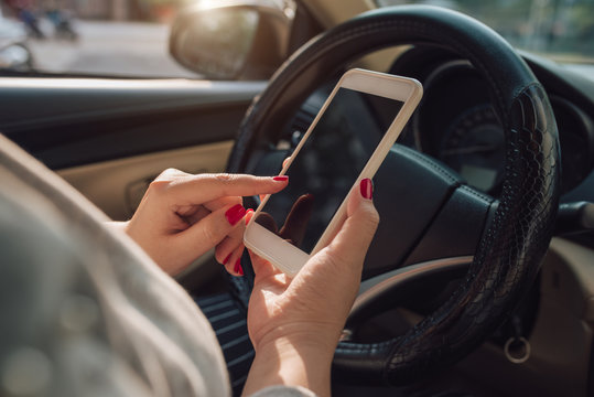 Mockup image of woman hand using mobile smartphone with blank screen while driving car and leaving home. clipping path.