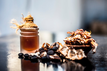 Tamarind or imli in a clay bowl on wooden surface with its extracted herbal and organic detoxifying essential oil in a glass bottle.