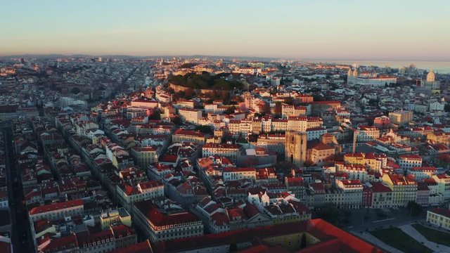 Aerial view; drone flight forward to the ancient building with brown rooftops; sunset time in Lisbon; beautiful winter evening in Portuguese capital; Alfama oldest historic district; view from above