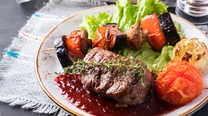 Beef steak with grilled vegetables and red sauce on a plate. Copy space