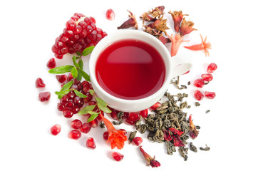 Parts of a pomegranate with pomegranate seeds and leaves, flowers, dry tea of carcade and full cup...
