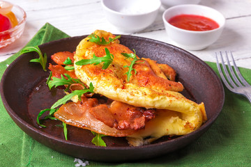 Delicious bacon omelette with arugula and colorful pickled tomatoes.Close up