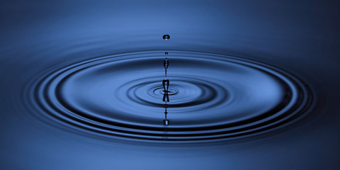 Blue water drop falling down. Blue abstraction background.