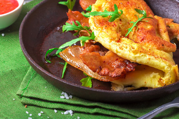 Delicious bacon omelette with arugula and colorful pickled tomatoes.Close up