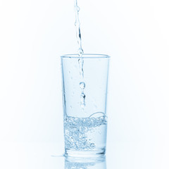 Pouring water into glass on white background.