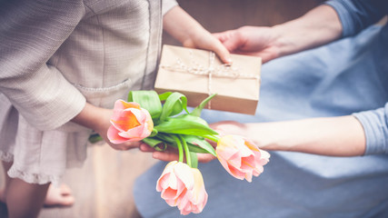 Banner Happy Mother's Day. Little girl congratulates mom and gives a gift and flowers tulips. Toning. Selective focus