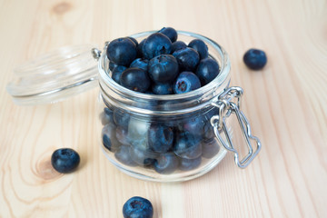 Blueberries in a glass jar on a wooden background with copy space