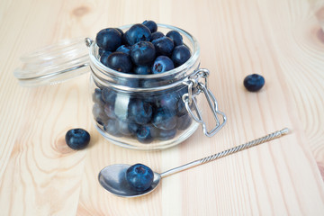 Blueberries in a glass jar on a wooden background with copy space