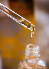 Cosmetic serum. Drop falls from a pipette into a cosmetic bottle.