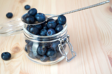 Blueberries in a glass jar on a wooden background with copy space
