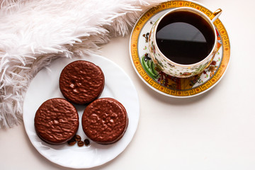 Chocolate cakes on the white plate and cup of hot black coffe. Top view.