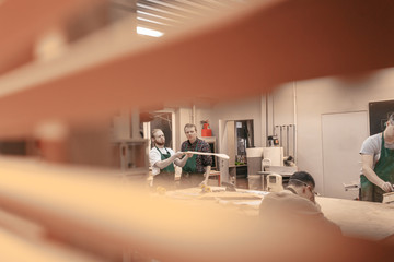 Two male carpenters a teacher and a student are working on a new product in their carpentry workshop. Concept of creating a new wooden handmade goods