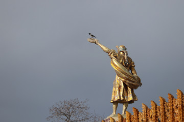 Fototapeta premium Statue of girl with wreath on the top of pavilion Ukraine (also known as Agriculture) after restoration on exhibition VDNH in Moscow, dramatic sky background. Soviet art and symbols, USSR history
