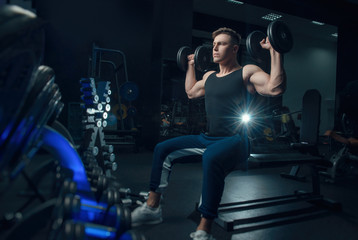 the sporty boy trains with dumbbells