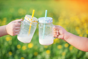 Bottles with milk in children's hands. Childhood, happiness, summer