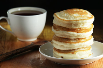 A stack of freshly backed pancakes and a cup of coffee