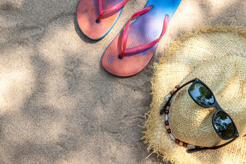 Summer vacation concept straw hat with sunglasses and  flip flop sandals  on sandy tropical beach -...