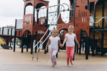 Little joyful caucasian girls playing together, having fun  in children park