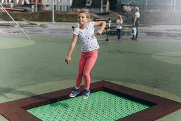 Cheerful adorable girl jumping outdoors in kindergarten.Happiness, sport, leisure, childhood, healthy concept