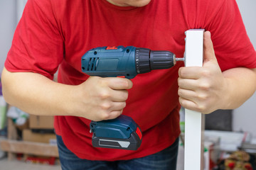 Man assembling DIY furniture using electric drill