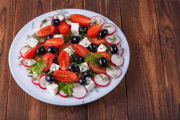 a plate of salad with red tomato, green pepper and cheese  on a wooden table
