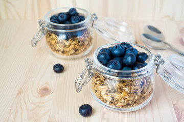 Oatmeal granola with blueberries in a glass jar on a wooden background